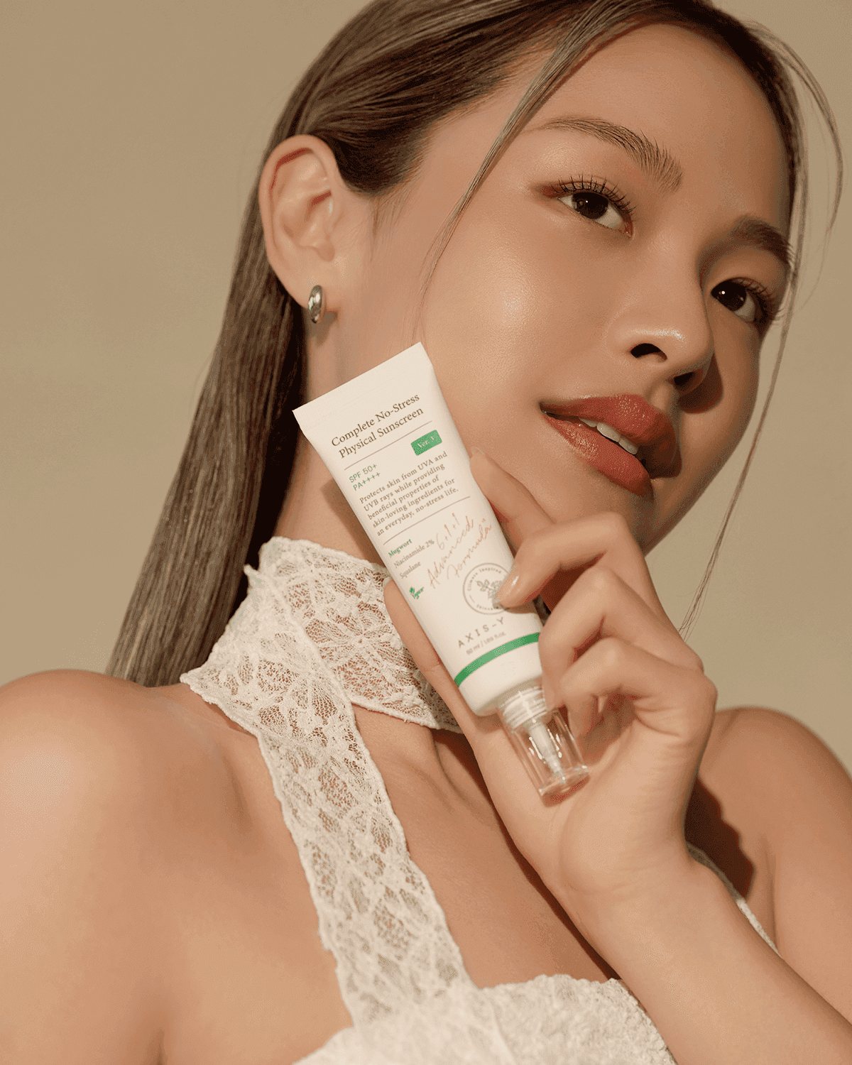 Model holding OTC version Complete No-Stress Physical Sunscreen V.3, highlighting its skin-enhancing benefits and lightweight formula for a radiant complexion.