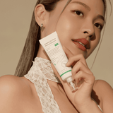 Model holding OTC version Complete No-Stress Physical Sunscreen V.3, highlighting its skin-enhancing benefits and lightweight formula for a radiant complexion.