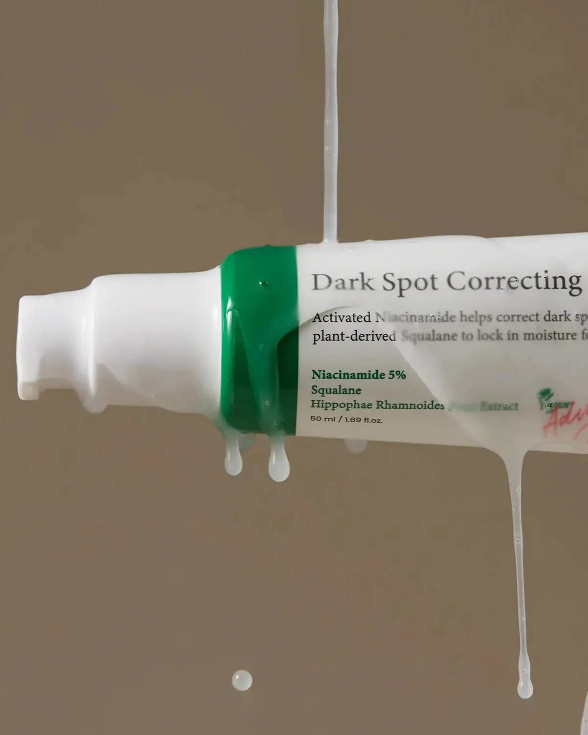 Close-up of Dark Spot Correcting Glow Serum with niacinamide and squalane, dripping to highlight its hydrating and brightening formula.