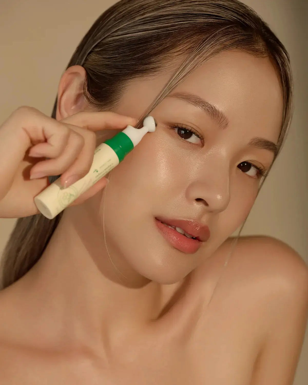 Model applying Vegan Collagen Eye Serum with a cooling applicator, promoting hydration and reducing dark circles for youthful eyes.